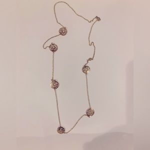Gold color necklace with disc that has a pretty pattern on it